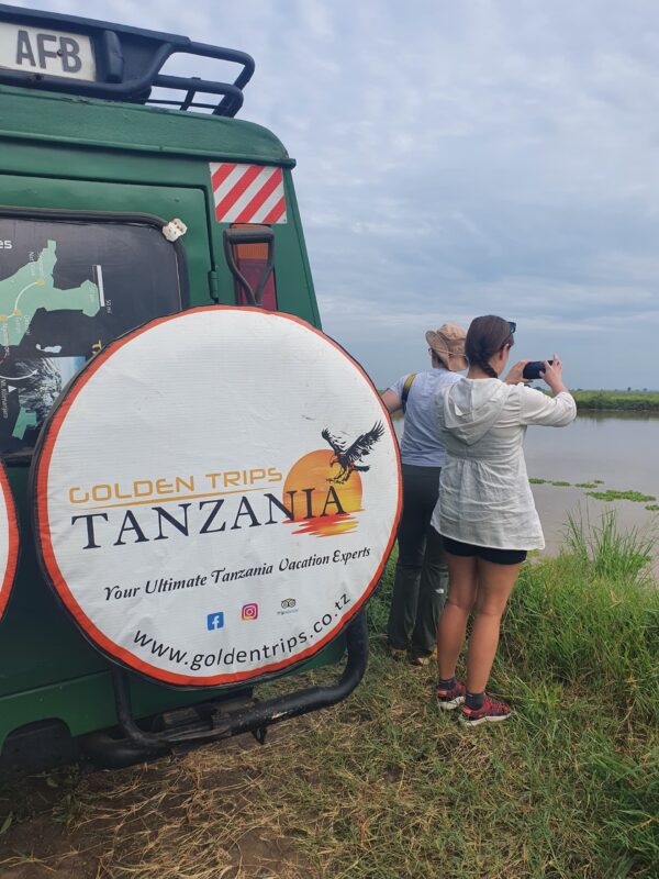A woman taking a picture of a lake with her phone